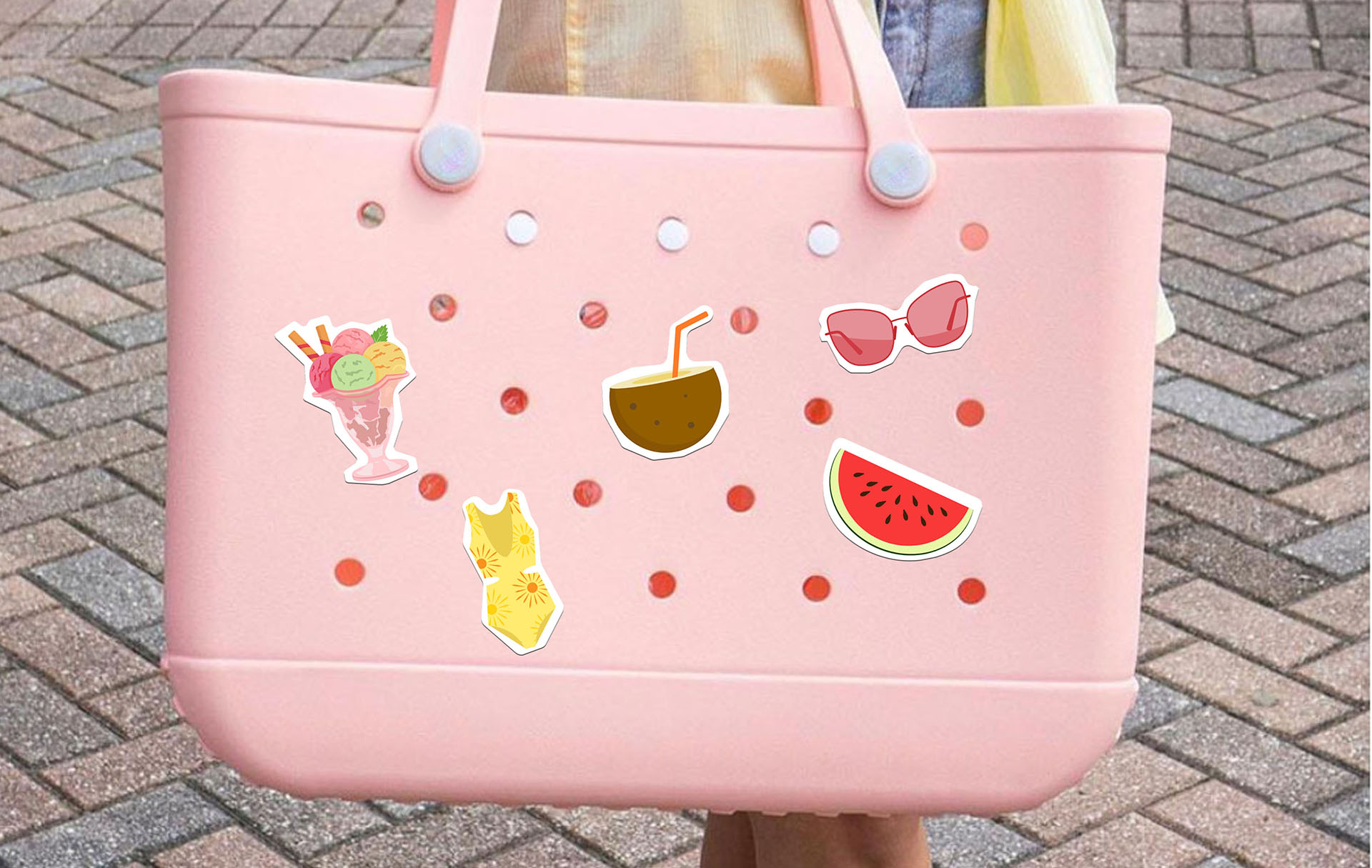 Pink tote bag with summer-themed stickers including sunglasses, watermelon, coconut, swimsuit, and tropical drink.