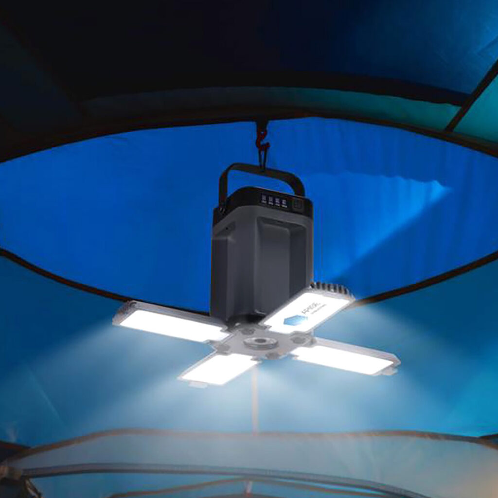 LED camping lantern hanging from the ceiling of a blue tent, illuminating the interior with bright white light.