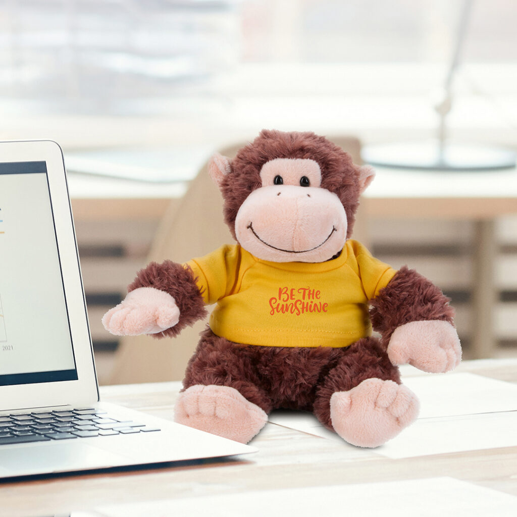 Plush monkey wearing a branded T-shirt, highlighting collectible gift shop merchandise and small keepsake souvenirs for travelers.
