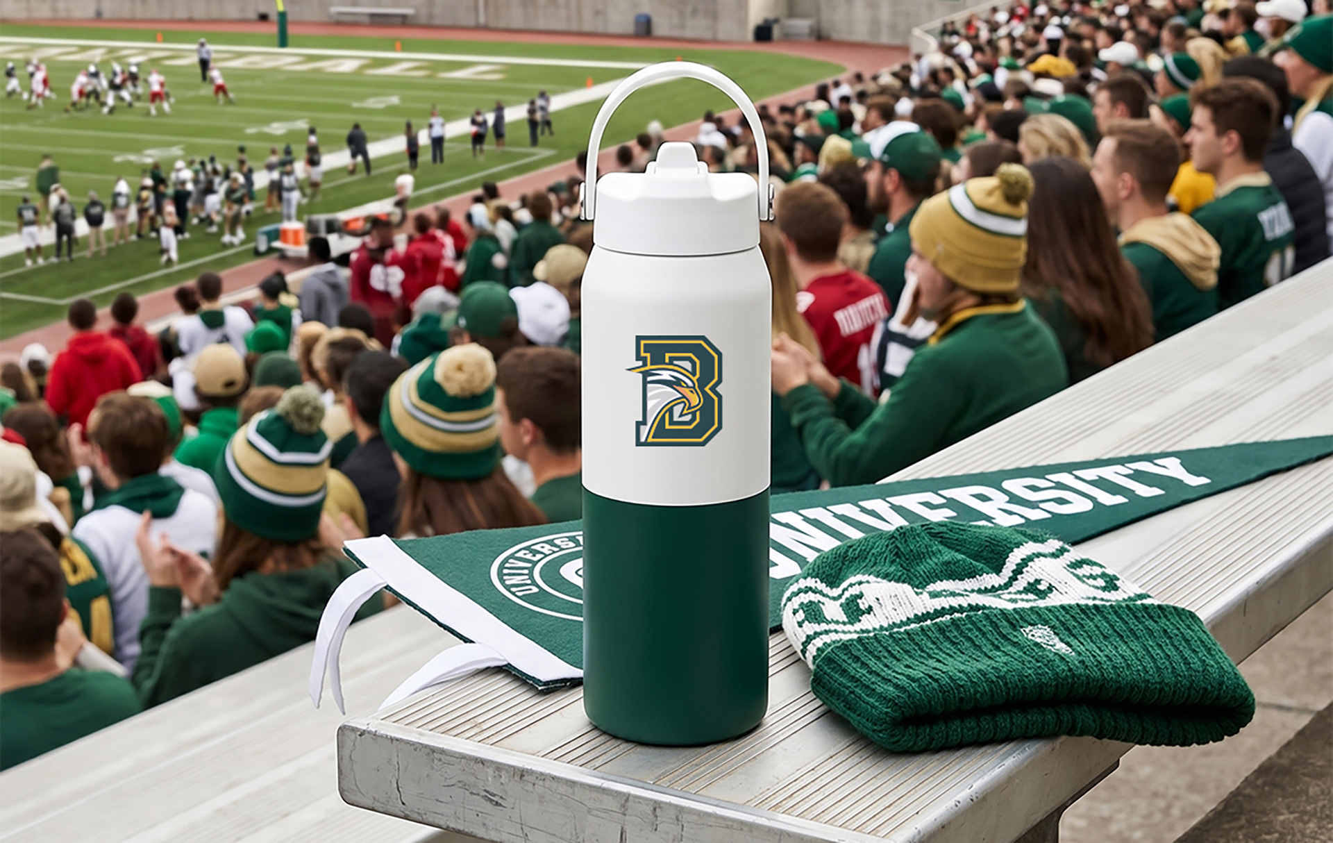 Branded university merchandise including a logo water bottle, knit beanie, and pennant displayed in stadium bleachers during a college football game.