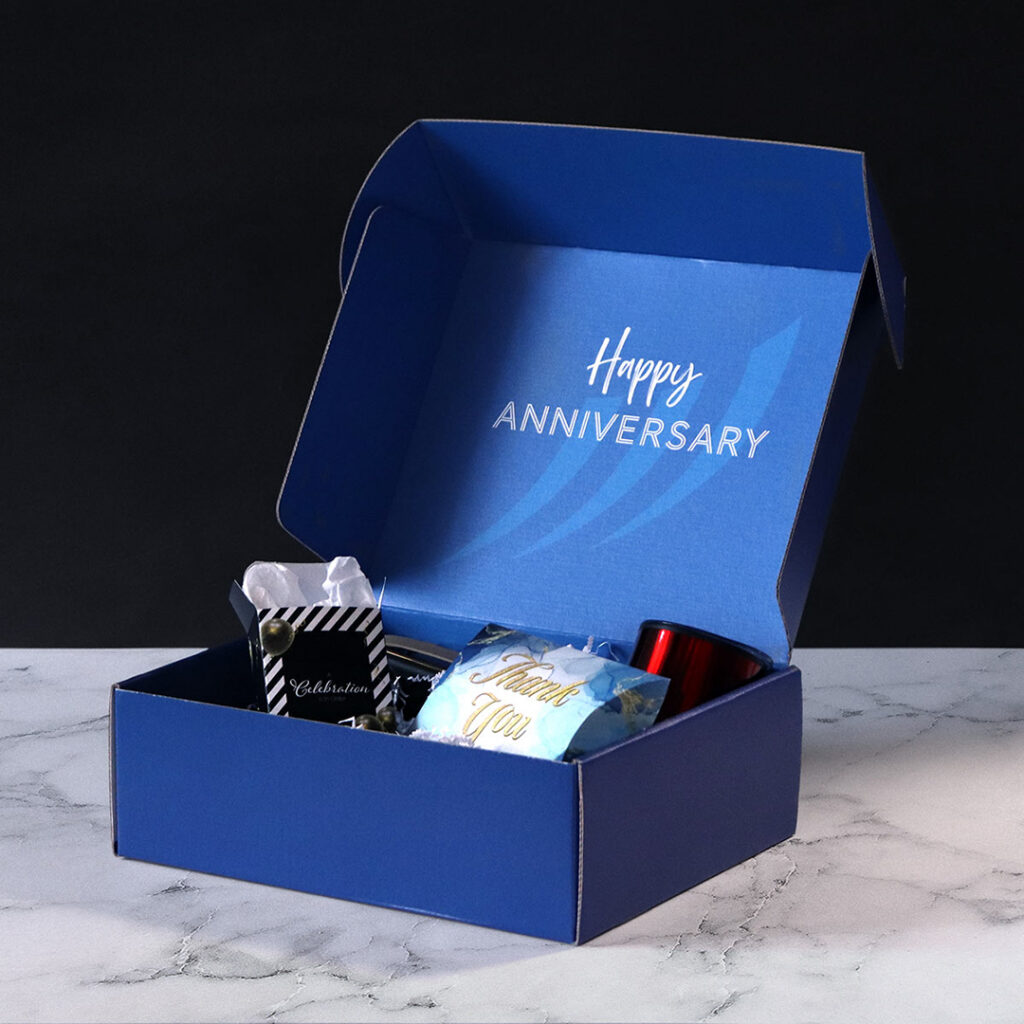 Custom corrugated mailer box with branded interior printing and anniversary-themed gift items, showcasing premium custom packaging for employee and client appreciation gifts.