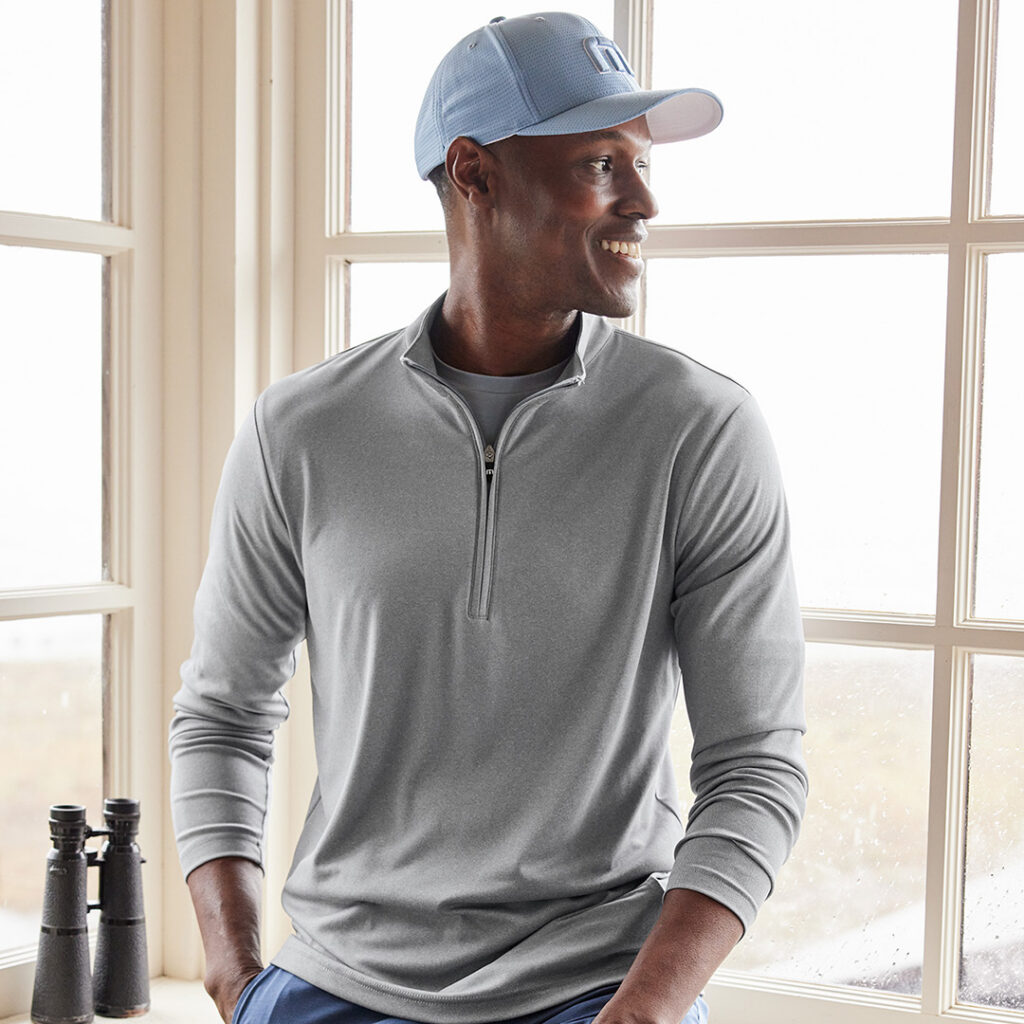 Performance quarter-zip pullover and matching cap in a refined cool gray shade, illustrating a versatile seasonless Autumn/Winter 2026 color for branded apparel and corporate uniforms.
