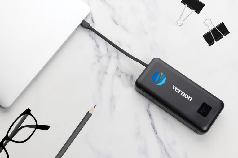 Branded portable power bank charging a laptop on a modern desk, showcasing a practical promotional gift for technology professionals.