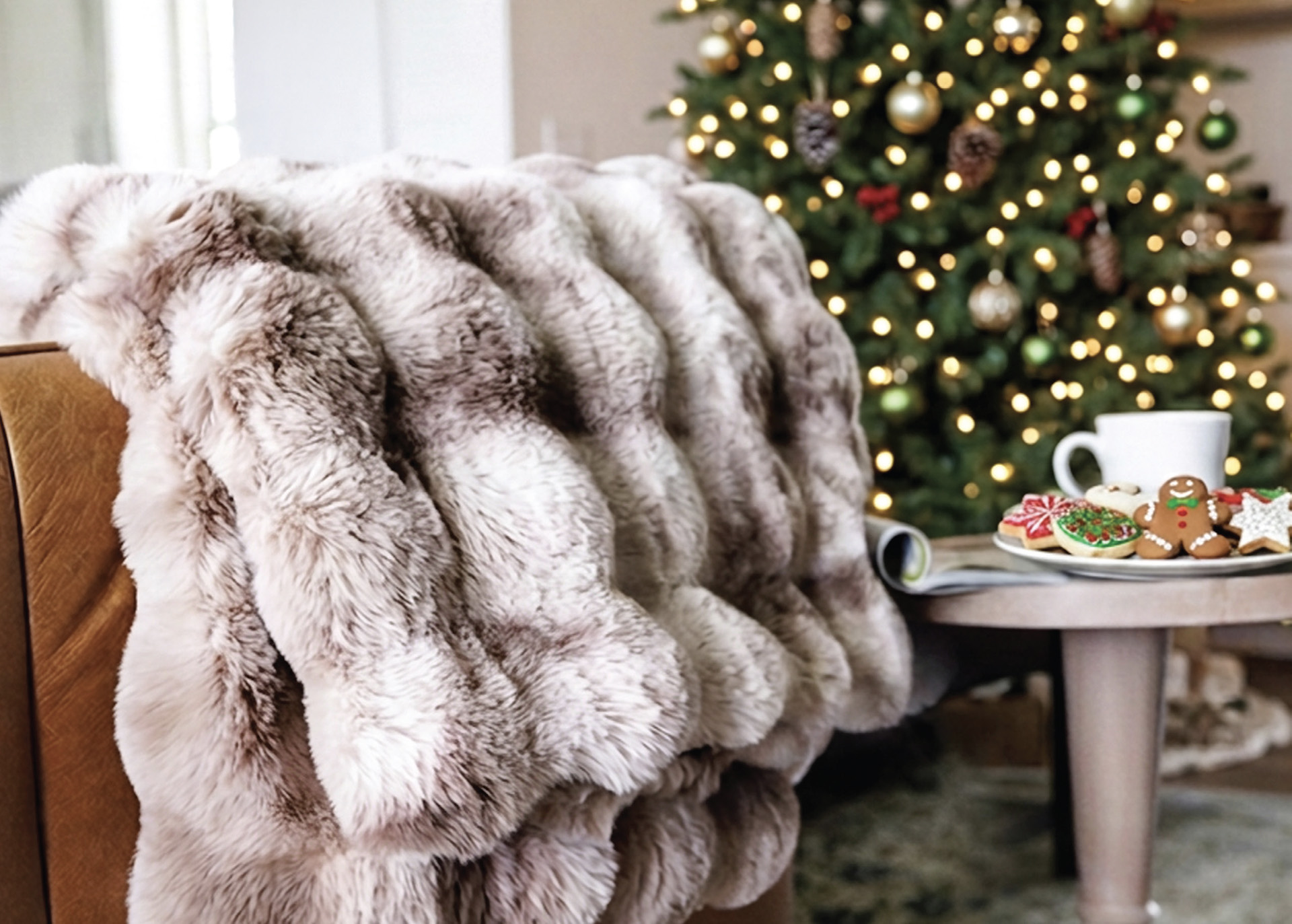 Plush faux fur throw draped over a chair beside holiday cookies and a warm beverage, creating a cozy winter scene that reflects a comfort-focused lifestyle gift.