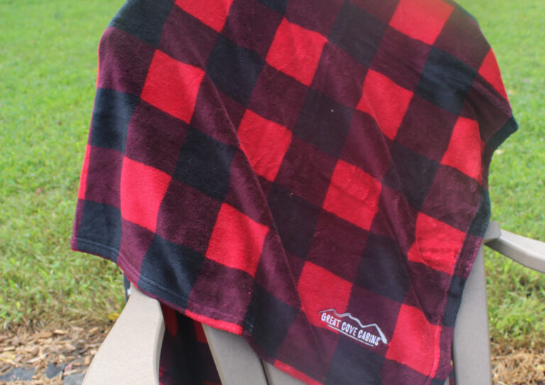 Red and black buffalo plaid fleece blanket draped over an outdoor chair, showcasing a classic plaid pattern popular in promotional products.