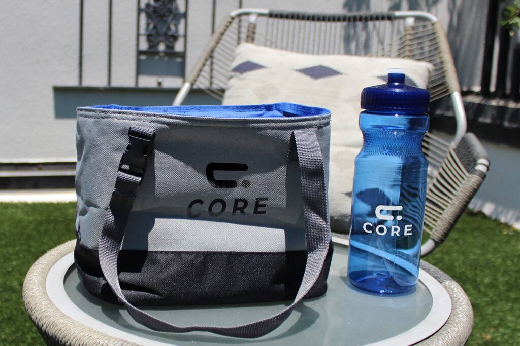 Branded cooler tote and water bottle used in an outdoor setting, showing how custom merchandise reinforces brand awareness through functional, everyday products.