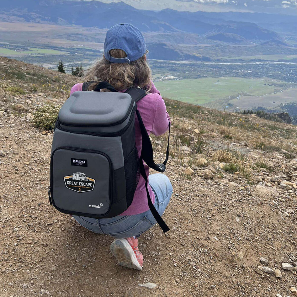 Person wearing a backpack cooler while overlooking a mountain landscape, representing a thoughtful gift for outdoor enthusiasts who enjoy hiking, camping and exploration.