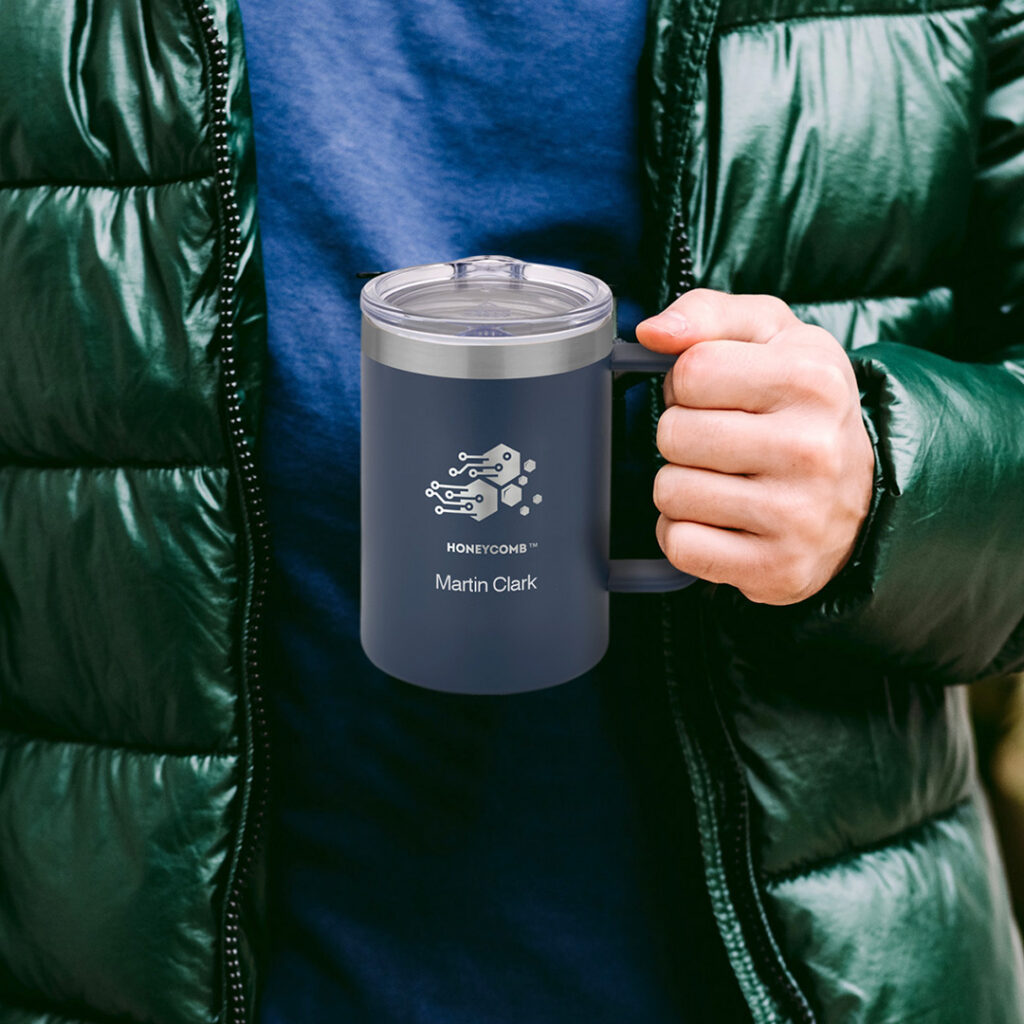 A personalized insulated travel mug held outdoors with a puffer jacket, showcasing a versatile gift for someone who enjoys everyday adventures and life on the go.